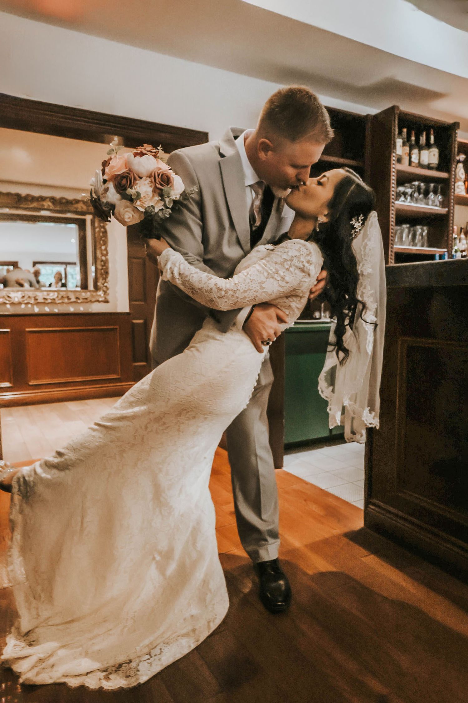 A romantic wedding dance dip pose in an indoor venue with wooden floors.