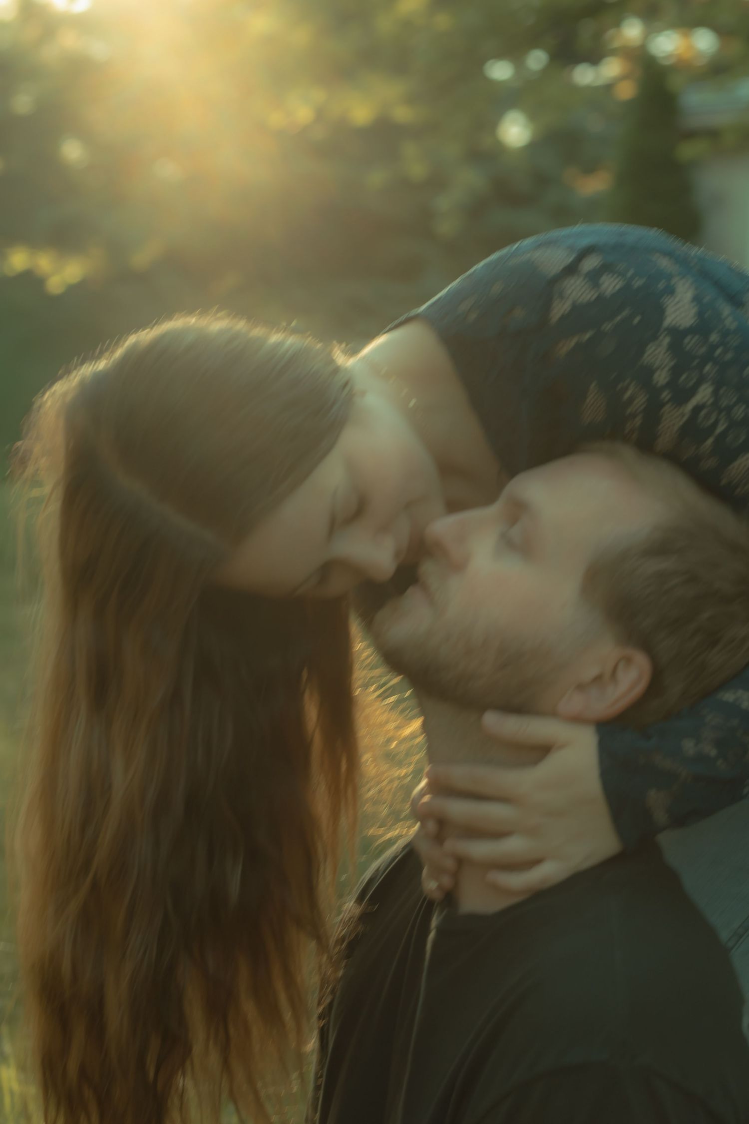 Romantic couple sharing a tender kiss in warm golden sunlight outdoors.