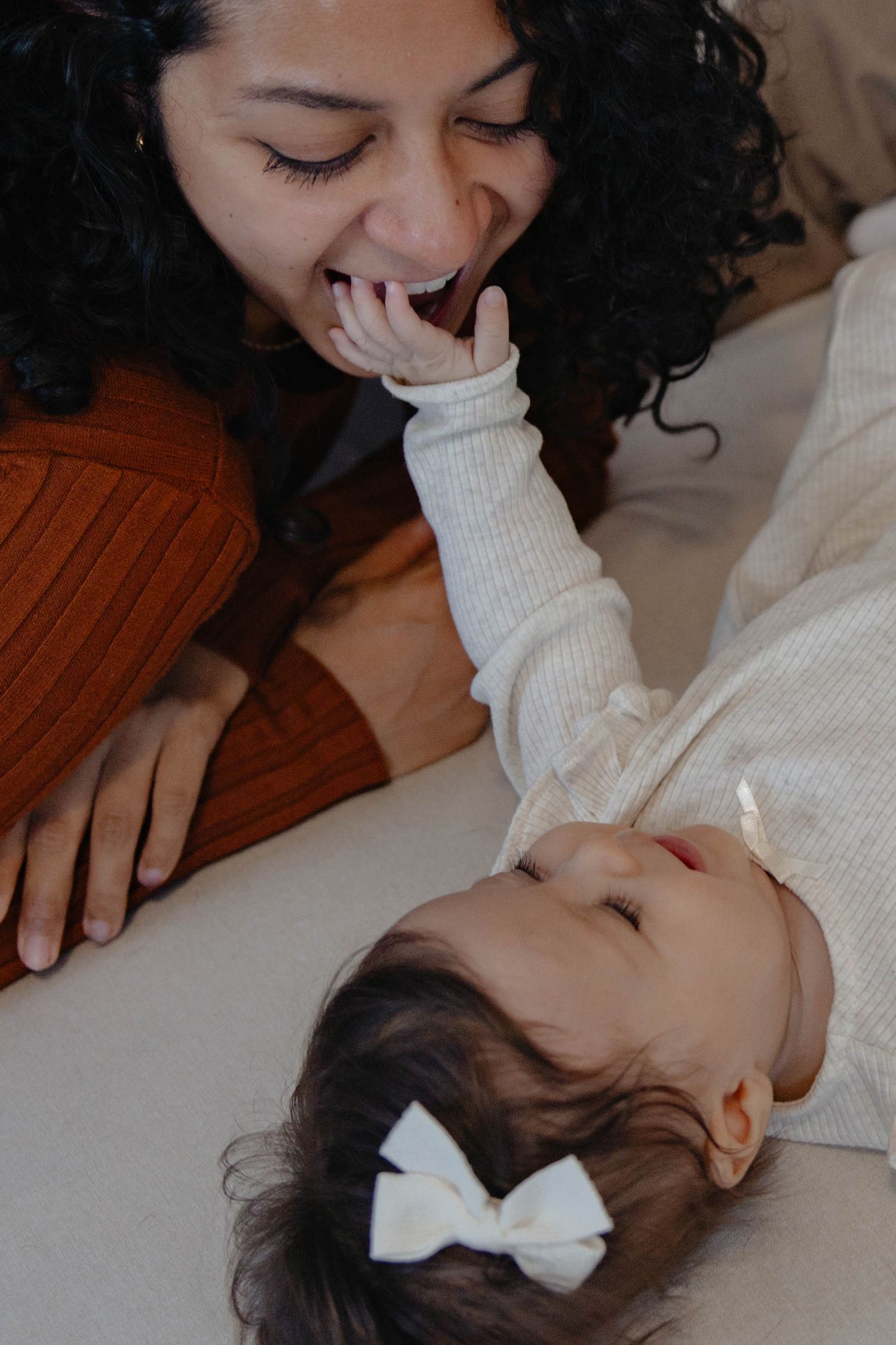 A tender moment between parent and child as they share laughter and affection while lying down together.