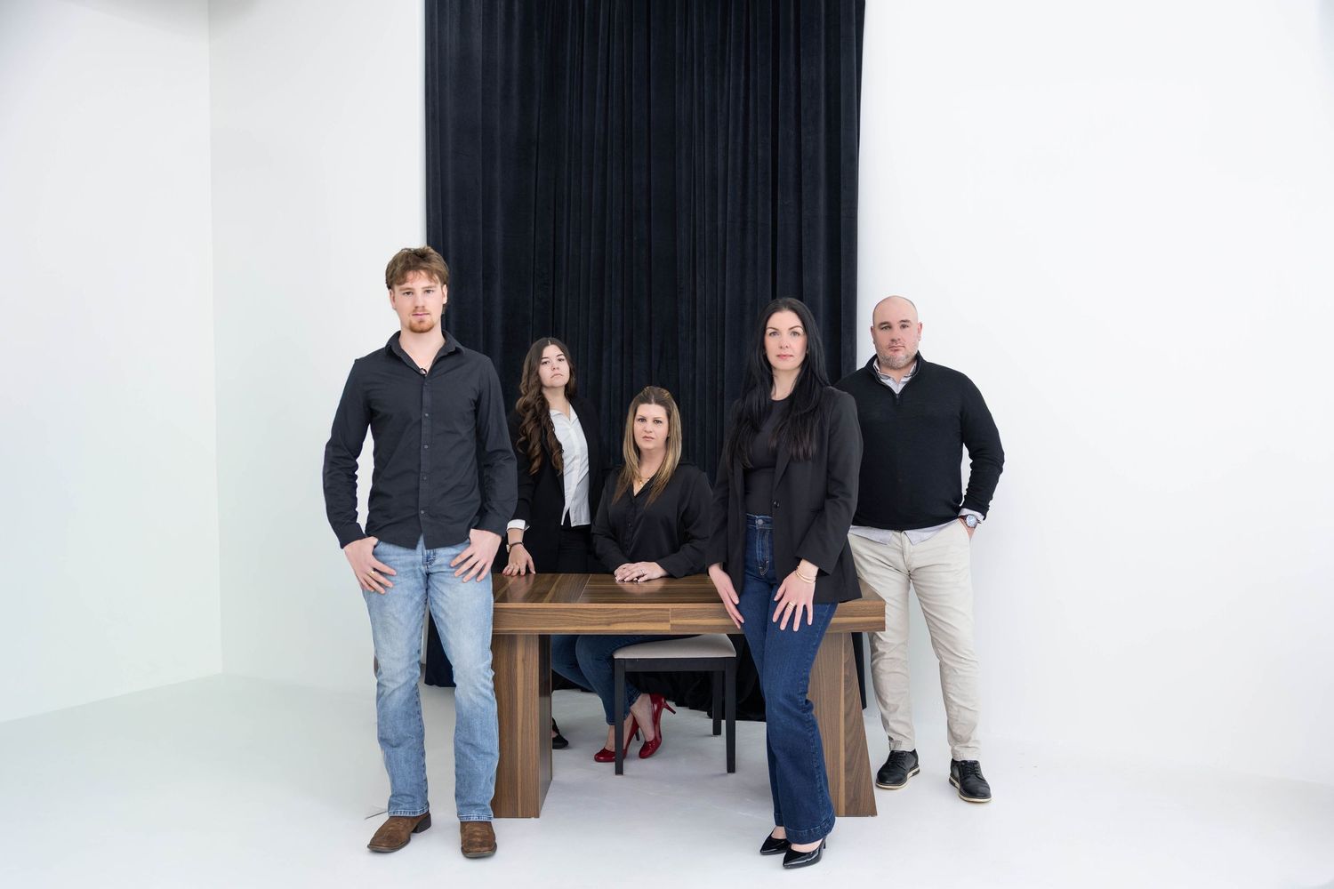 A group of people in casual attire pose together in a white studio setting.