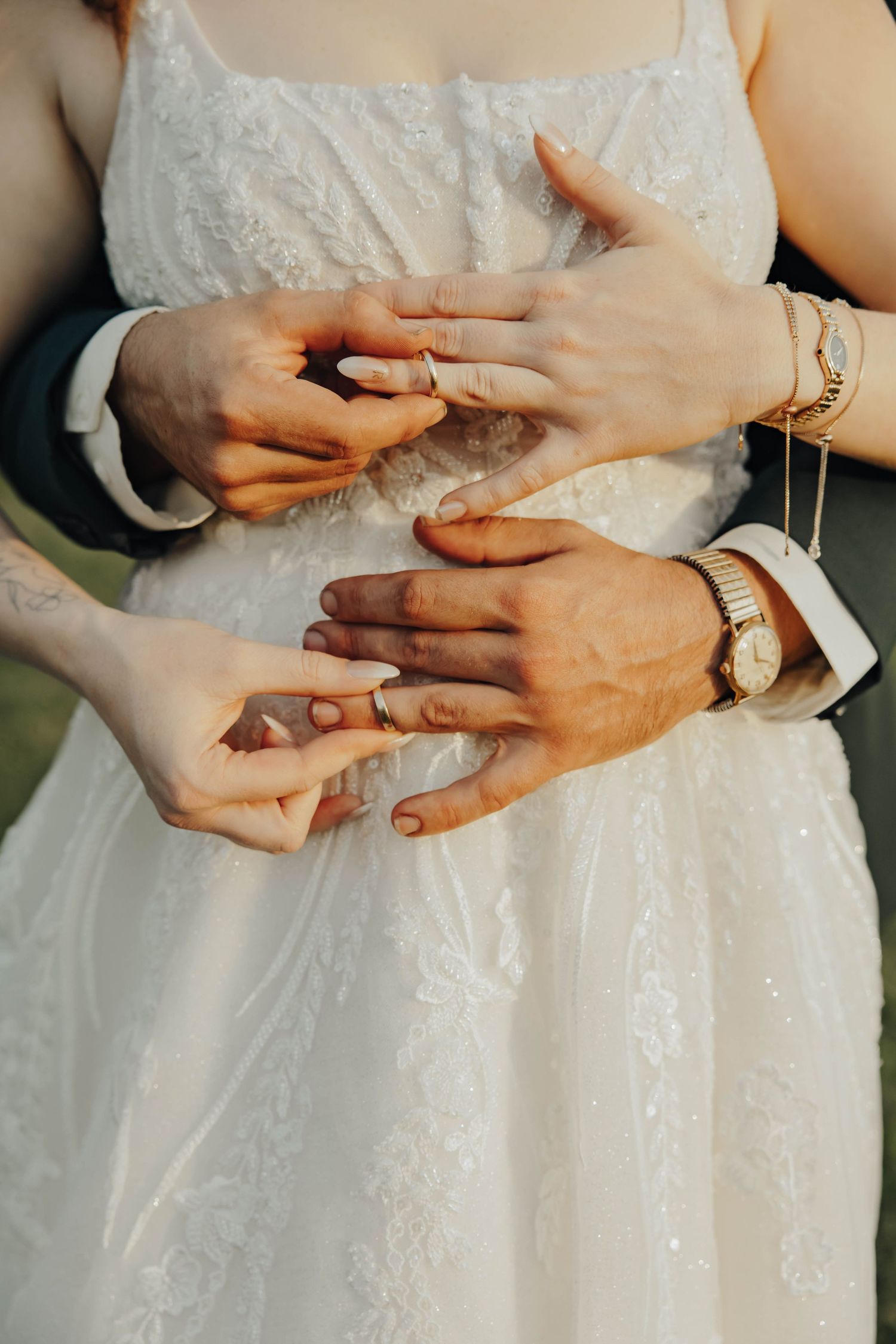 Close-up shots of hands with wedding rings against a white lace wedding dress.