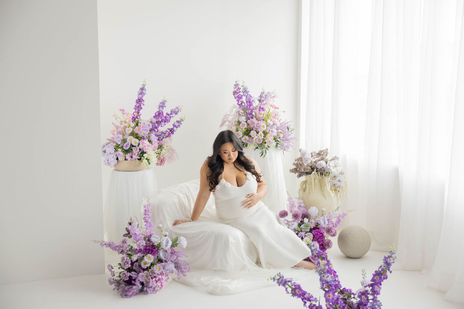 Elegant white wedding scene with purple delphinium flowers and soft curtains creating a romantic atmosphere.
