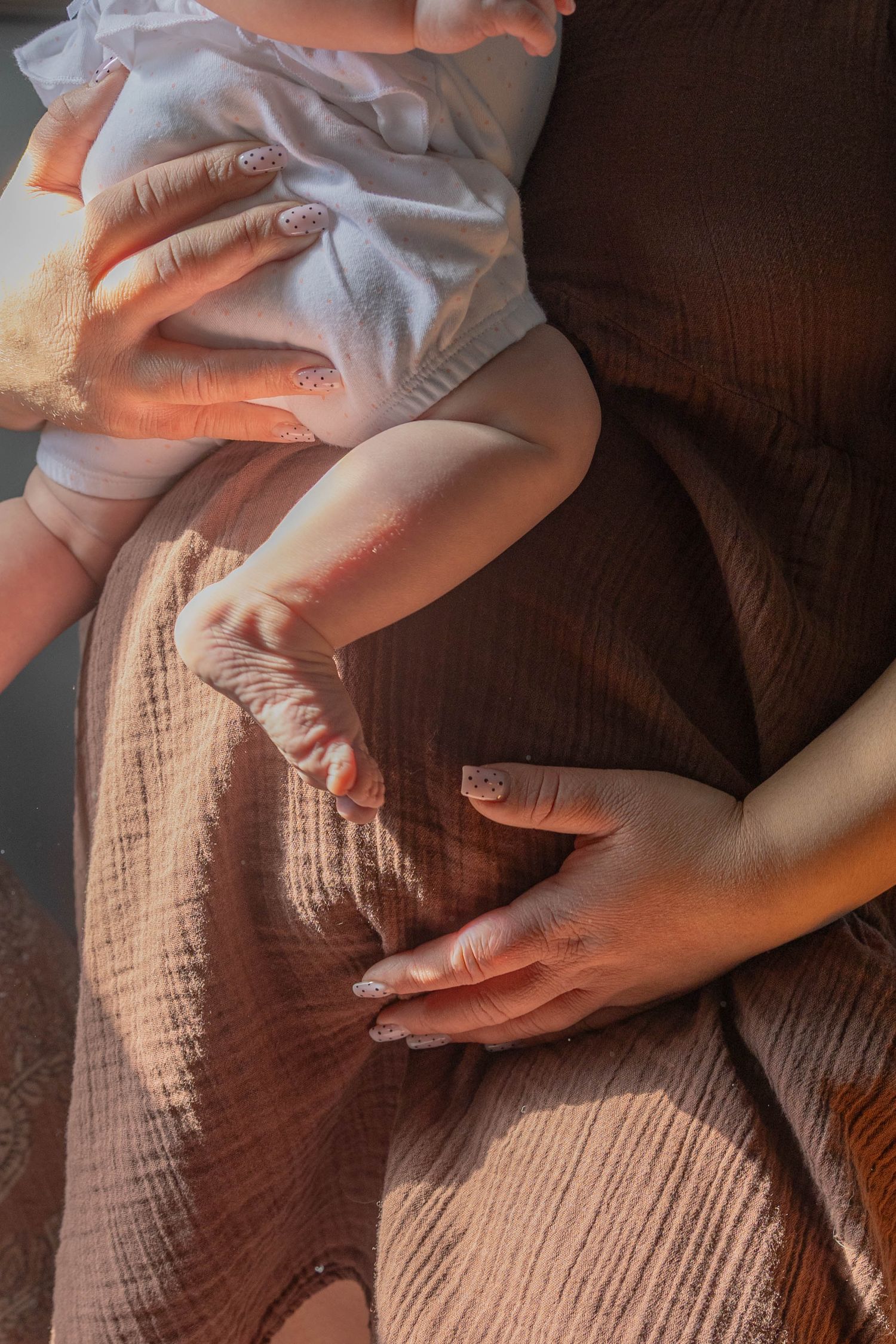 Close-up series of hands gently caressing a pregnant belly in warm lighting on textured fabric.