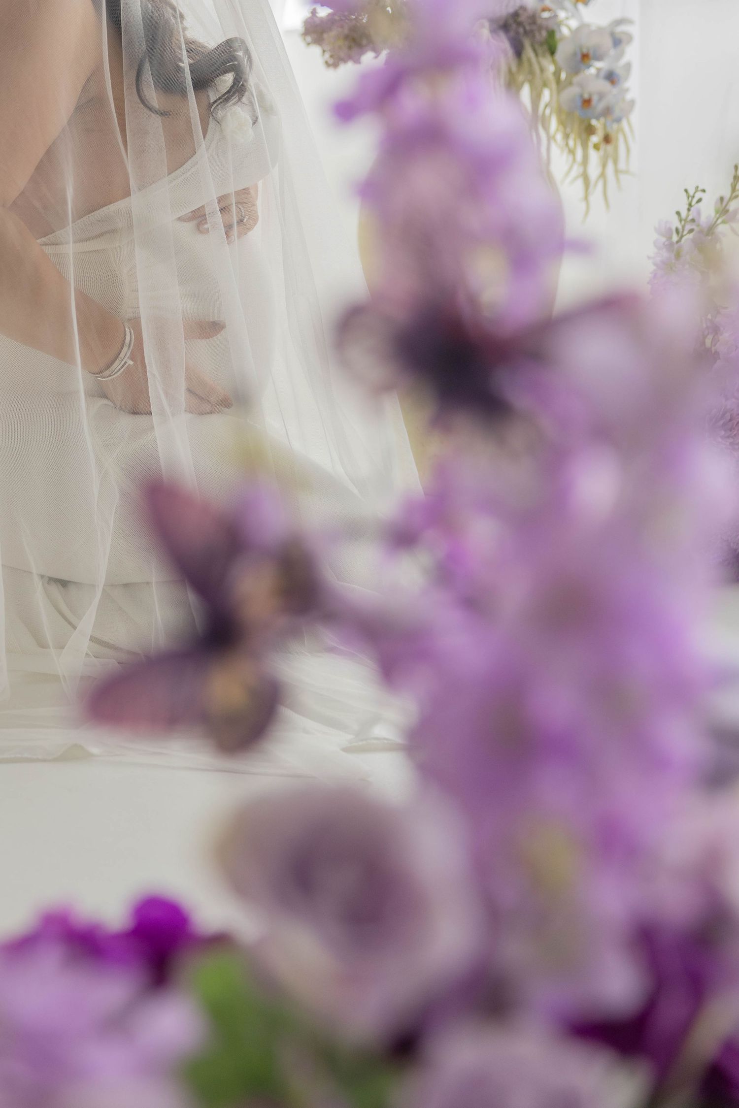 Dreamy purple wisteria flowers create a soft romantic backdrop for a wedding scene.
