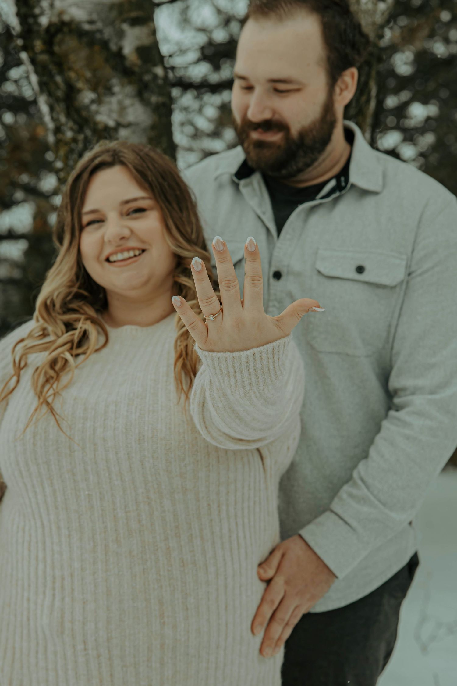 A couple shares playful and romantic moments in a winter setting wearing cozy sweaters.