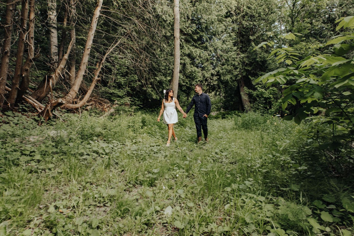 Two people walk together in a green woodland setting on a summer afternoon.