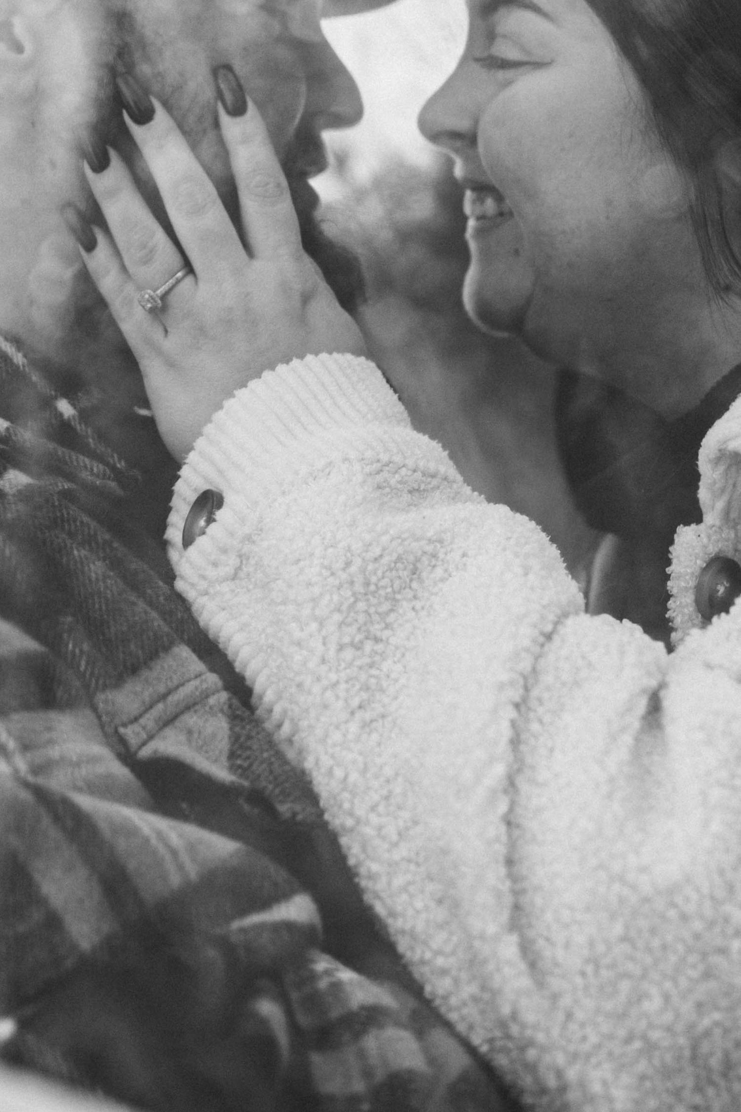 A tender black and white photograph shows a couple sharing an intimate kiss in a romantic moment.