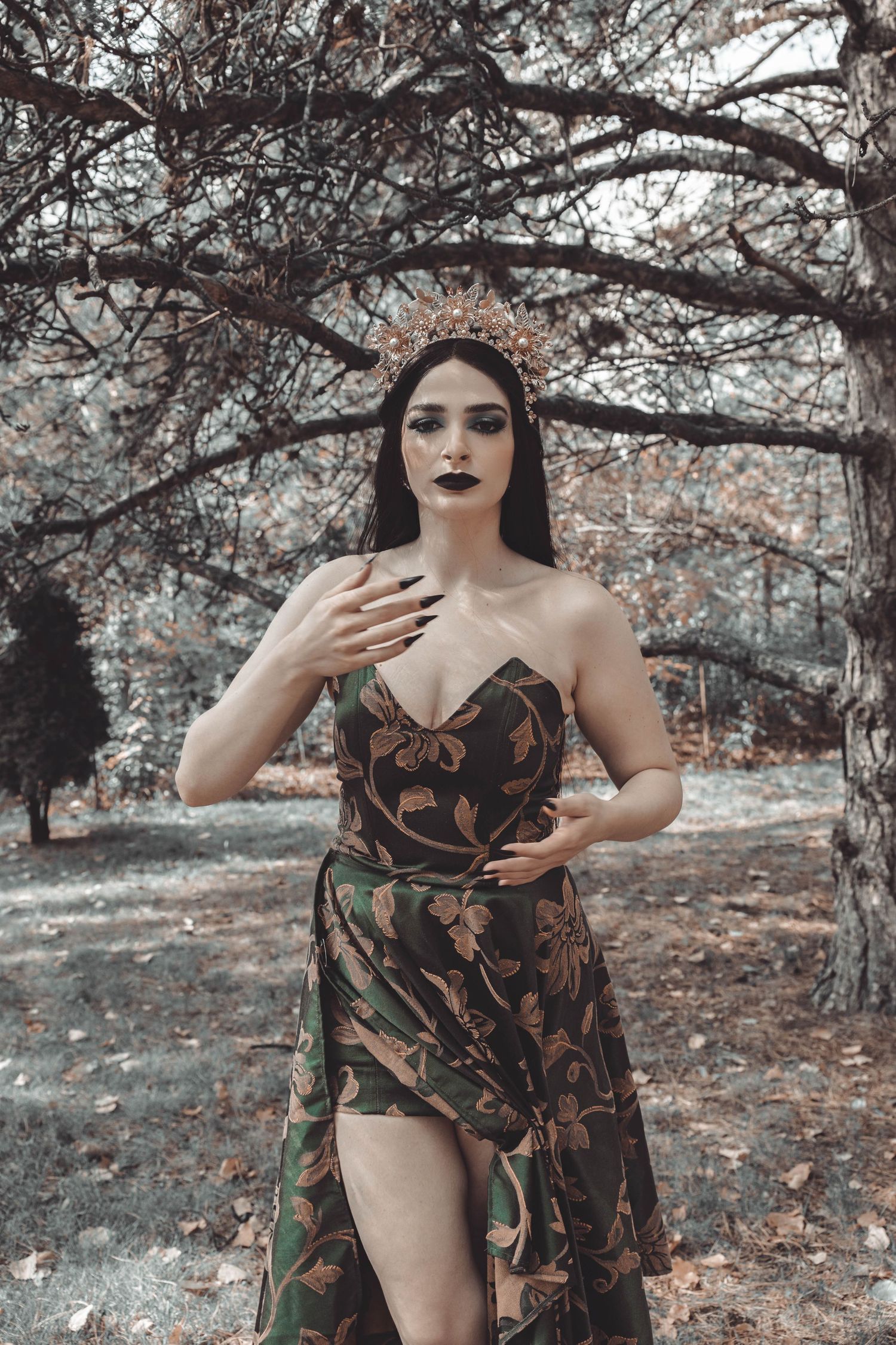 Artistic fashion photoshoot in autumn woods featuring floral dress and dramatic poses against muted natural backdrop.