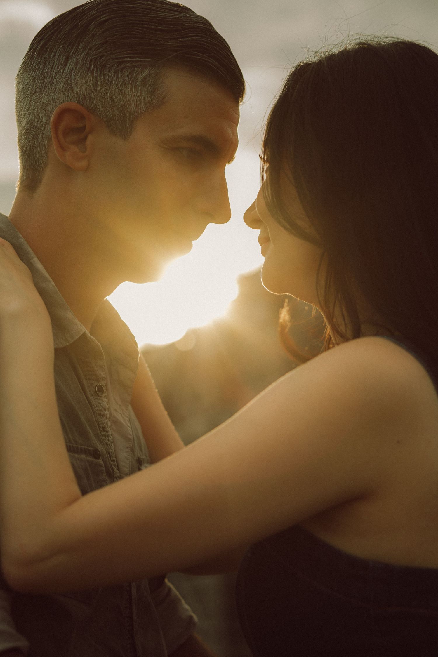 Romantic couple embracing face-to-face in golden sunset backlight.