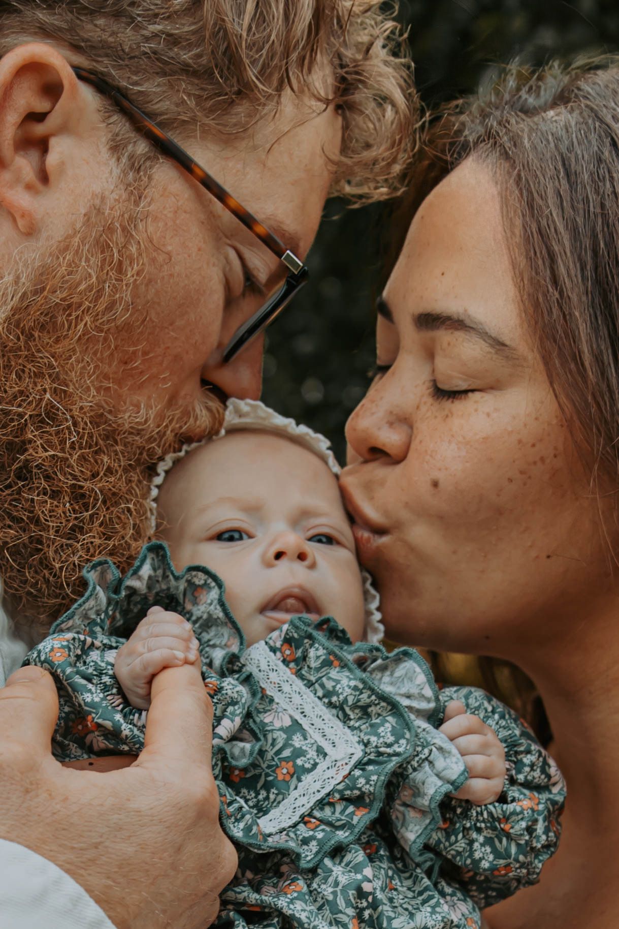 A sequence of intimate moments showing parents sharing loving kisses with their baby in turquoise clothing.