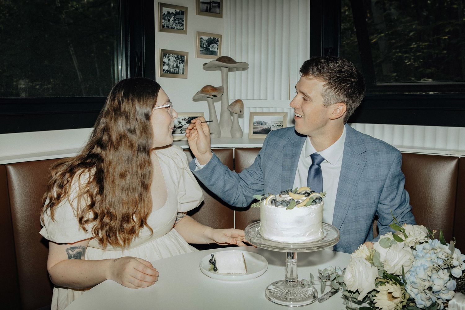 A playful wedding couple feeding each other cake at their reception.