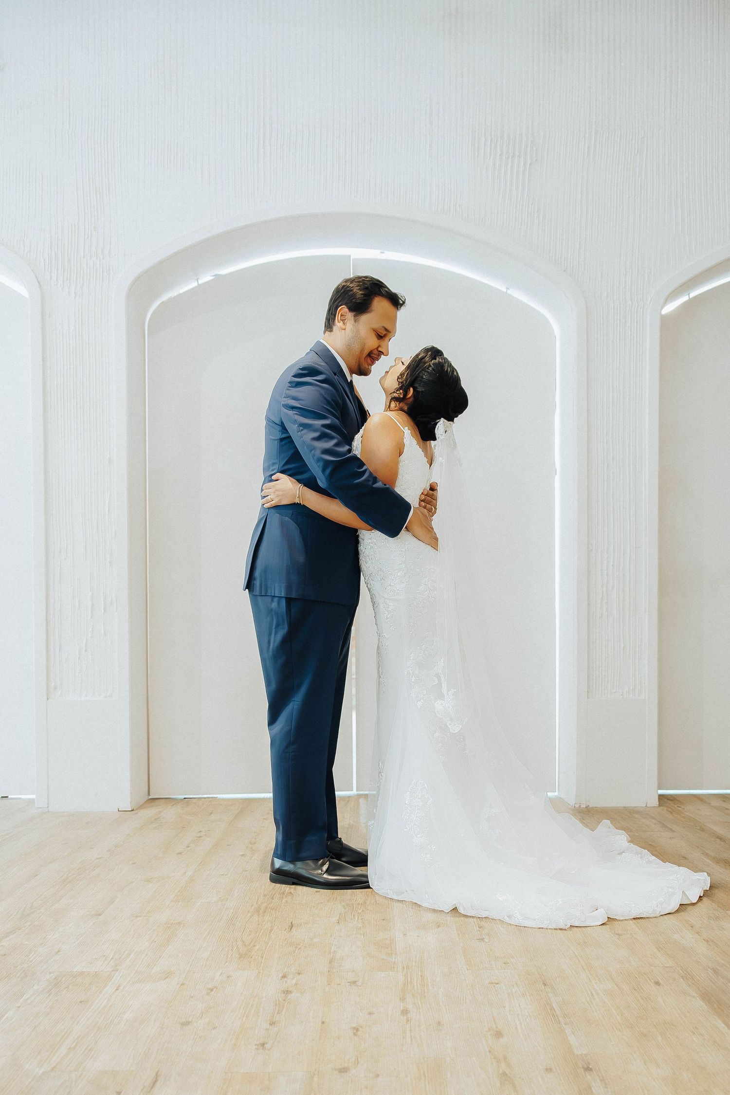 A series of four romantic wedding photos showing a couple in formal attire dancing gracefully in a bright white room.