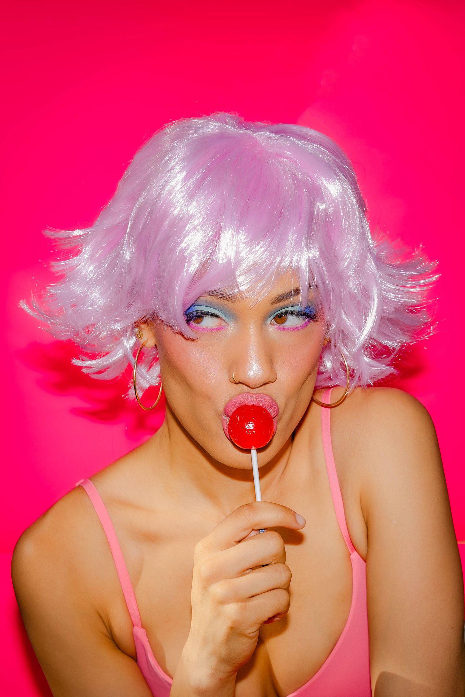 Fashion portrait series with pink background showing playful poses with a lollipop and light pink wig.
