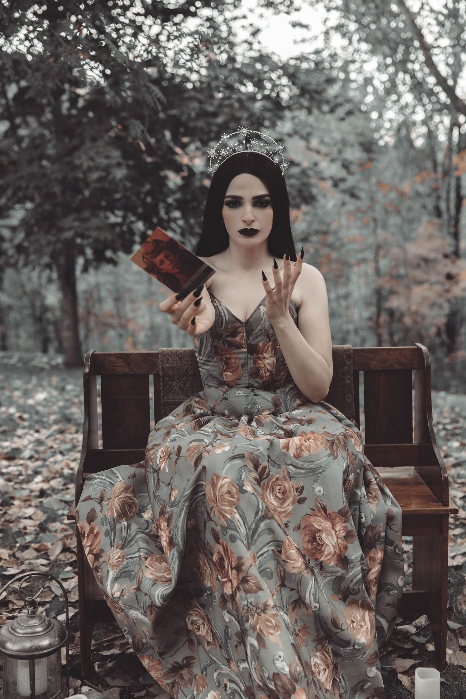Dramatic portrait on wooden bench featuring vintage-style floral dress in desaturated autumn setting.