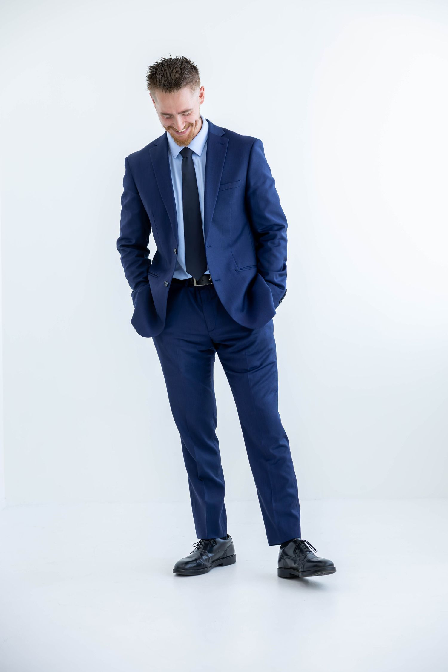 Professional wearing navy blue suit and dress shoes poses against white background in various stances.