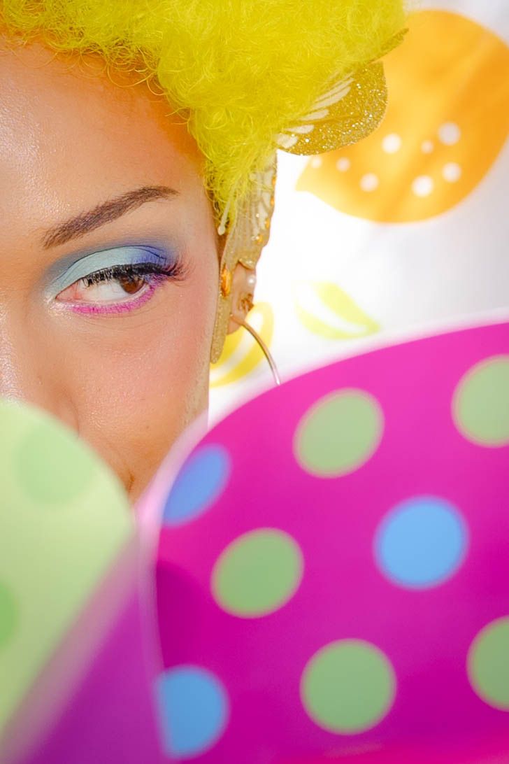 Close-up artistic shot with yellow hair and bright polka dot patterns in pink and blue tones.