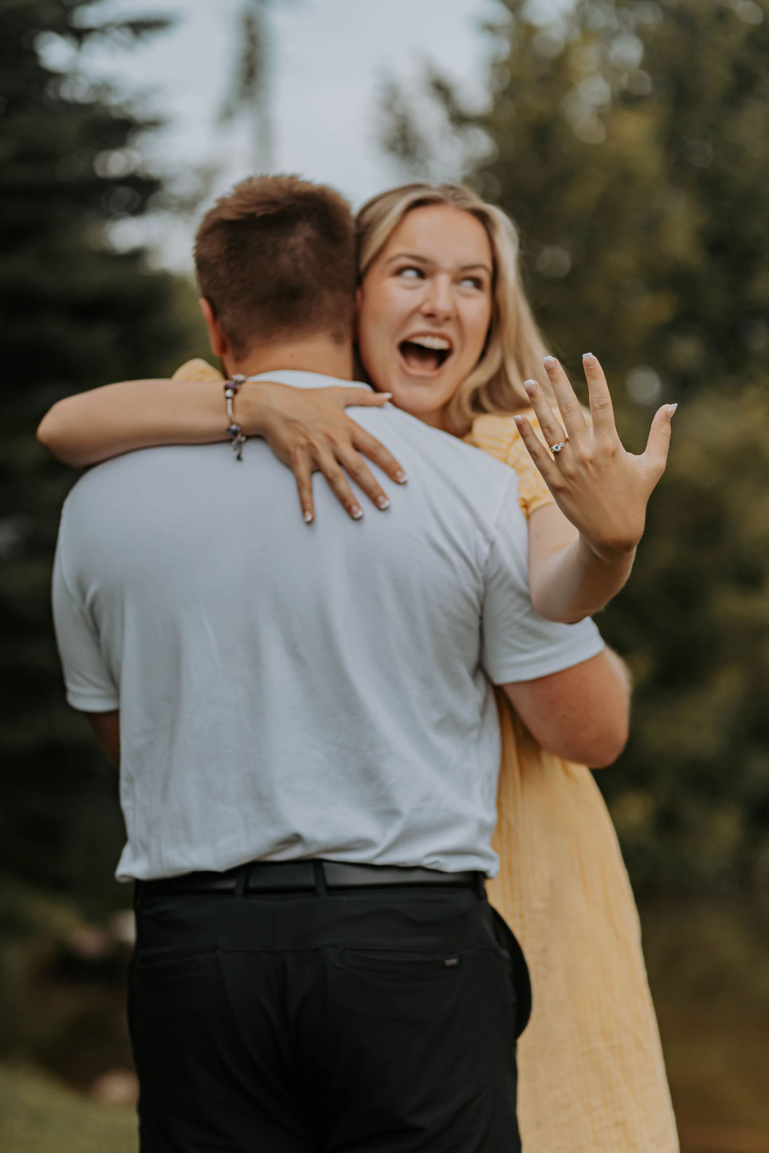 A couple embraces during an outdoor engagement or wedding photoshoot wearing white and black attire.