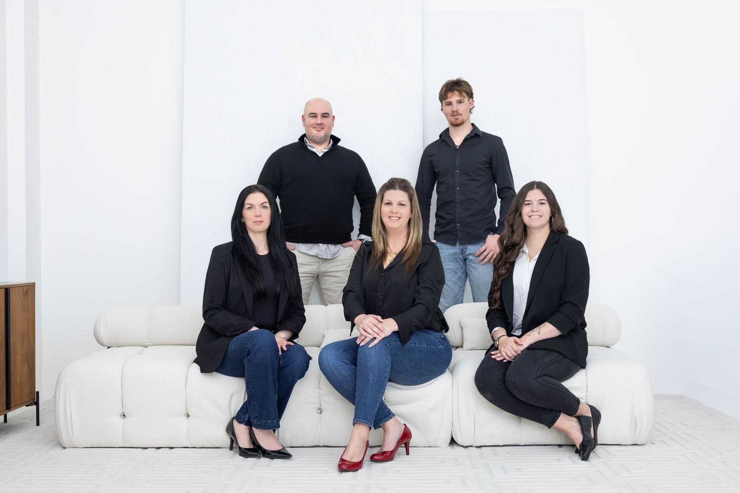 Group of business professionals sitting on white couches in a modern minimalist office setting.