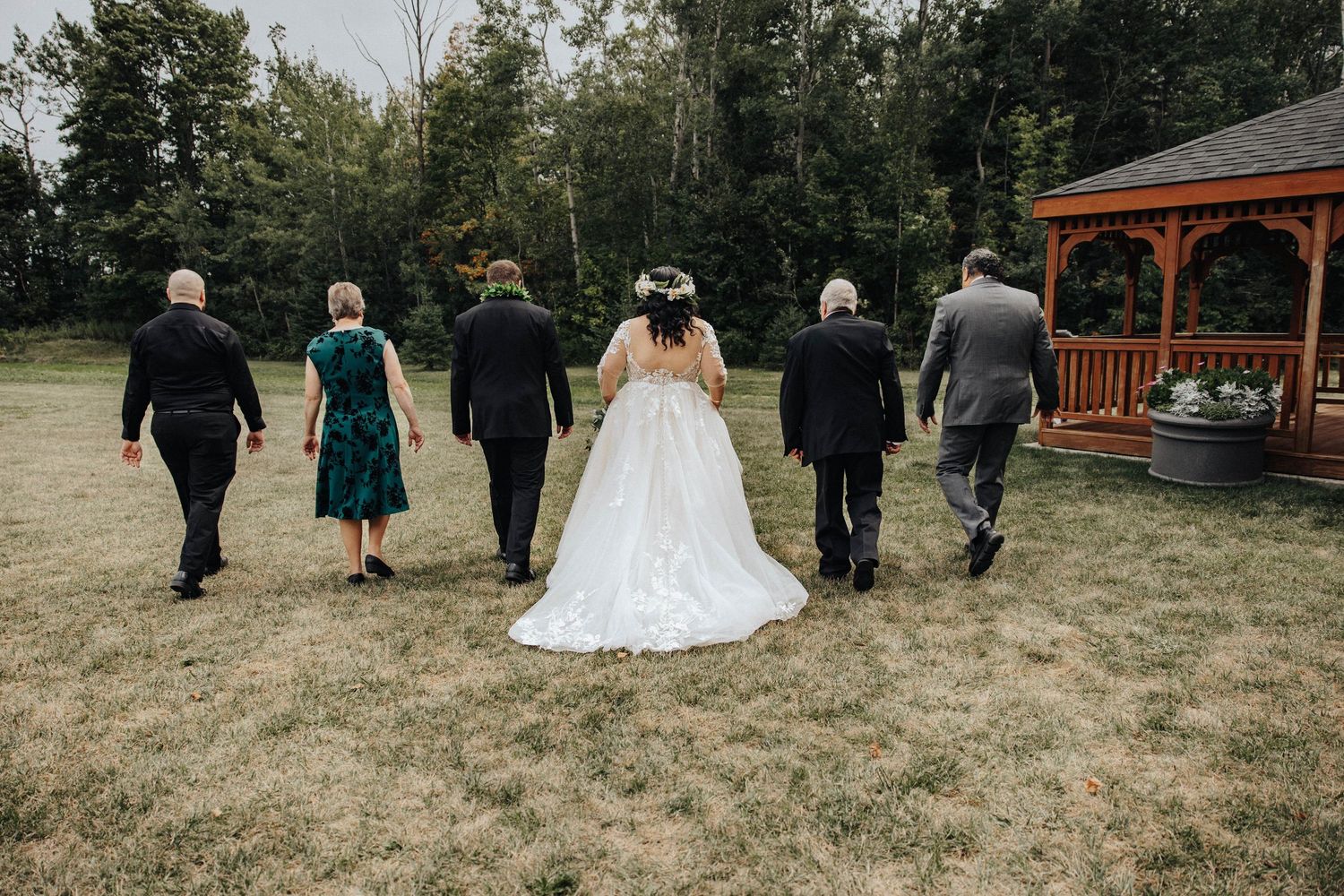 Wedding party members walk together across a rustic outdoor venue setting in autumn.