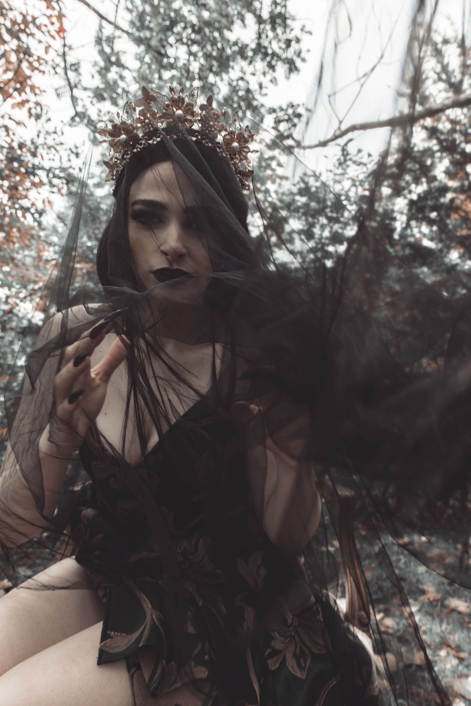 Artistic fashion portrait with black feathers and dramatic lighting creating a dark ethereal mood.