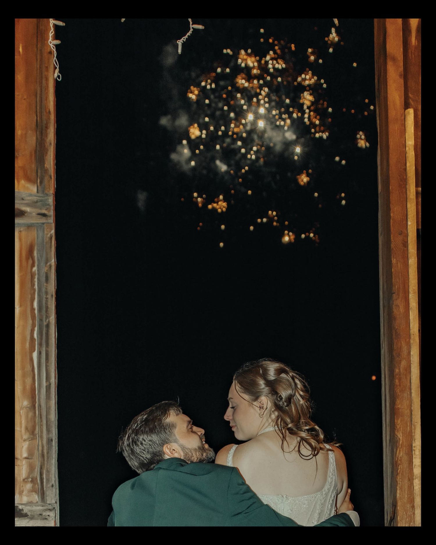 Couple sharing an intimate moment in a dimly lit room with glowing lights in the background.