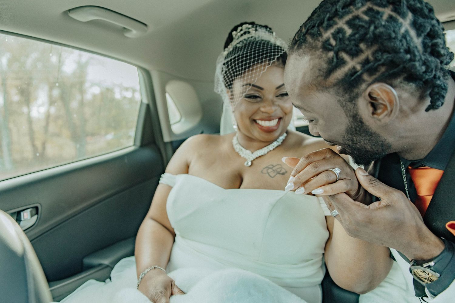 Couple sharing an intimate moment together in the backseat of a car during a wedding celebration.