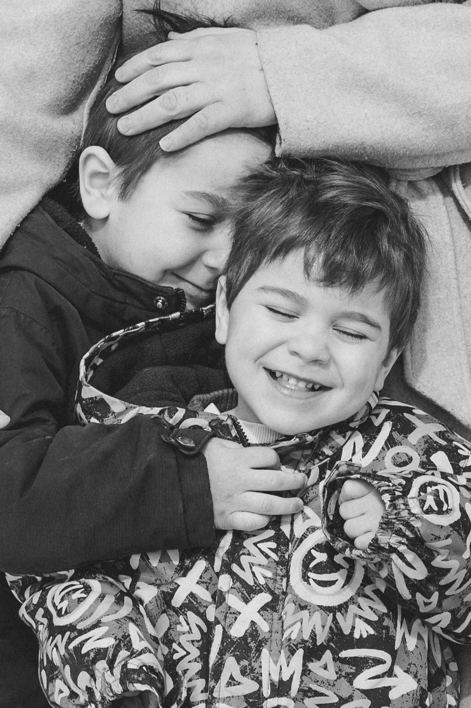 A black and white photo sequence shows a child lying down and making playful expressions while wearing a patterned shirt.