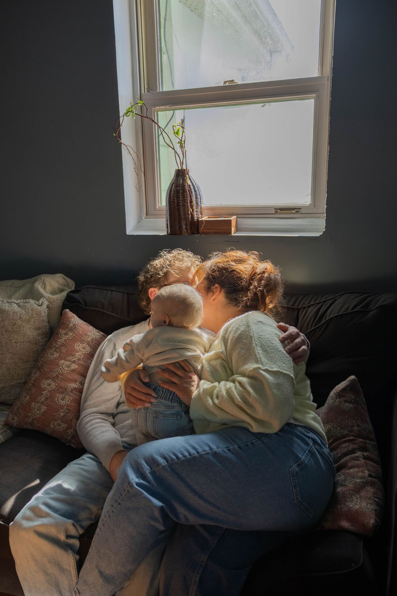 Three similar photos show people snuggling together on a dark couch in front of a window with natural light streaming in.
