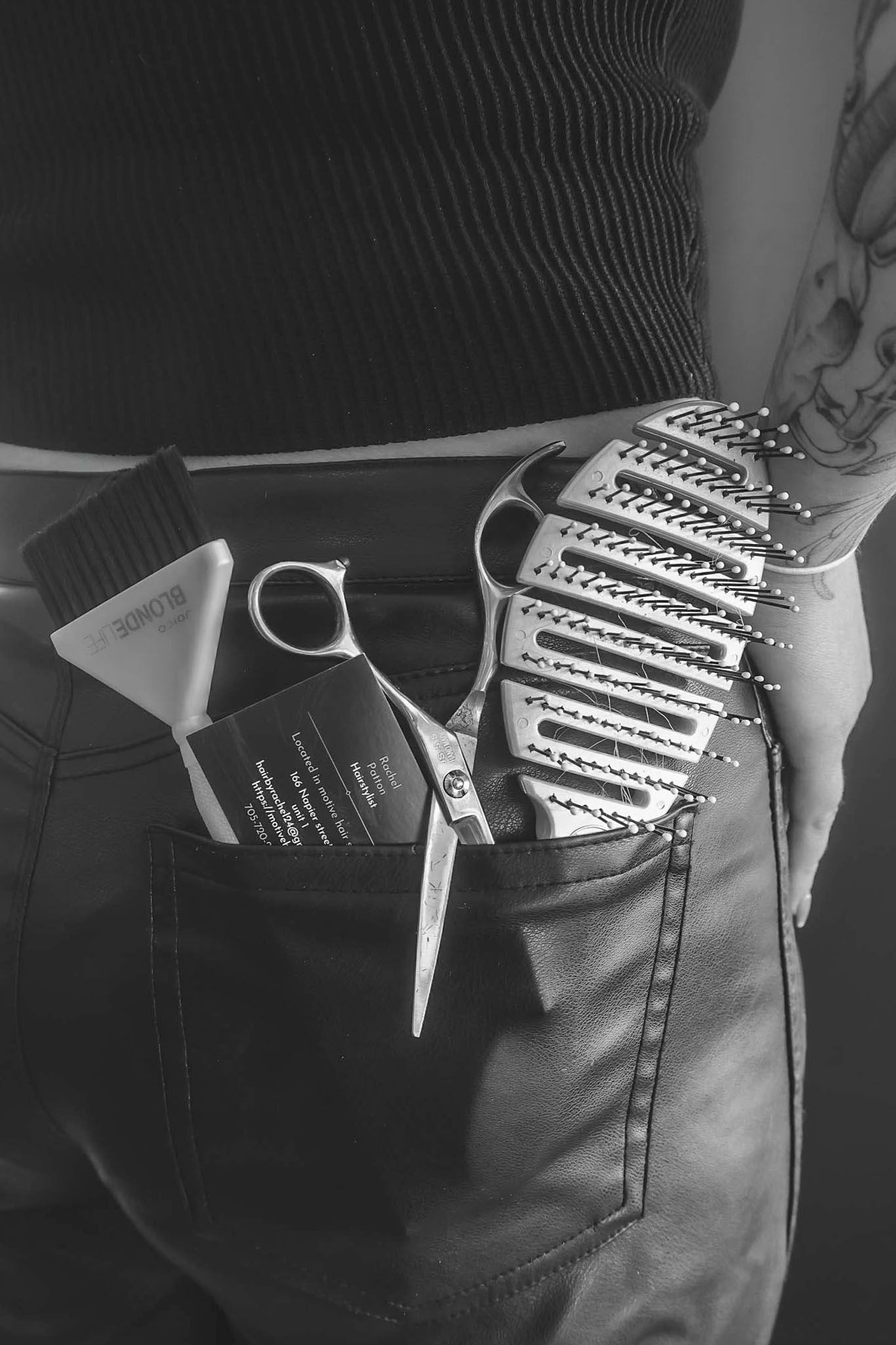 Close-up black and white shot of hairdressing tools in a leather pocket.