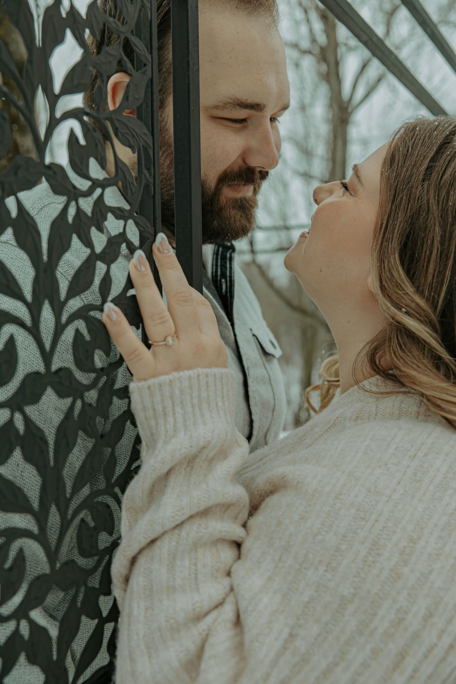 A romantic couple in cozy sweaters share tender moments through a series of intimate outdoor winter portraits.