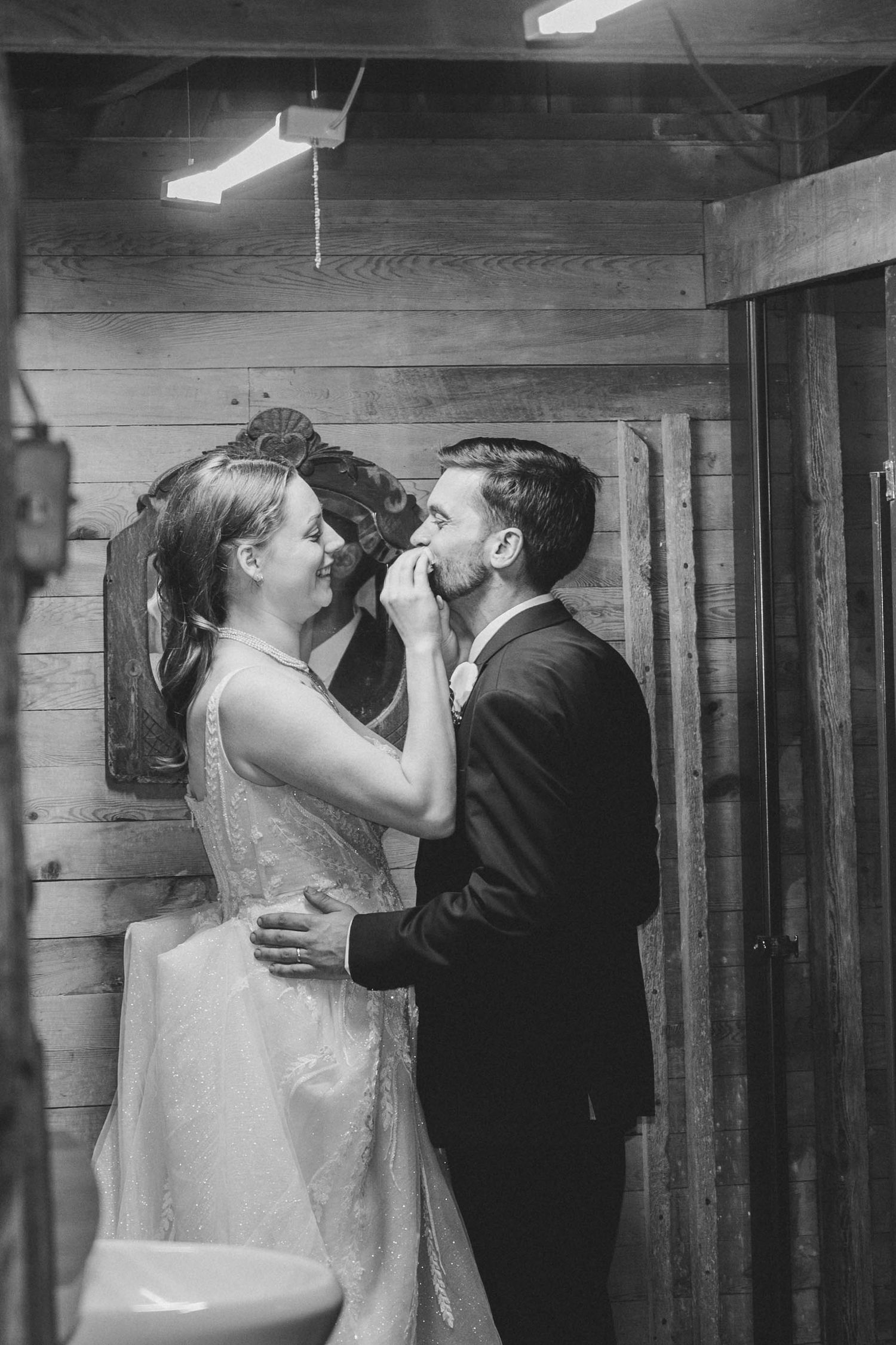 Black and white wedding photos show romantic moments between a couple in a rustic wooden interior setting.