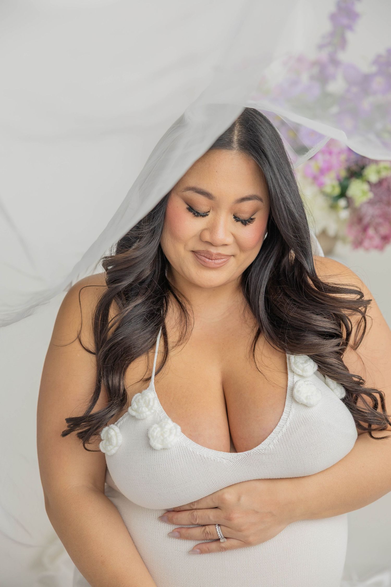 Intimate maternity portrait in white with delicate lace details and soft lighting.