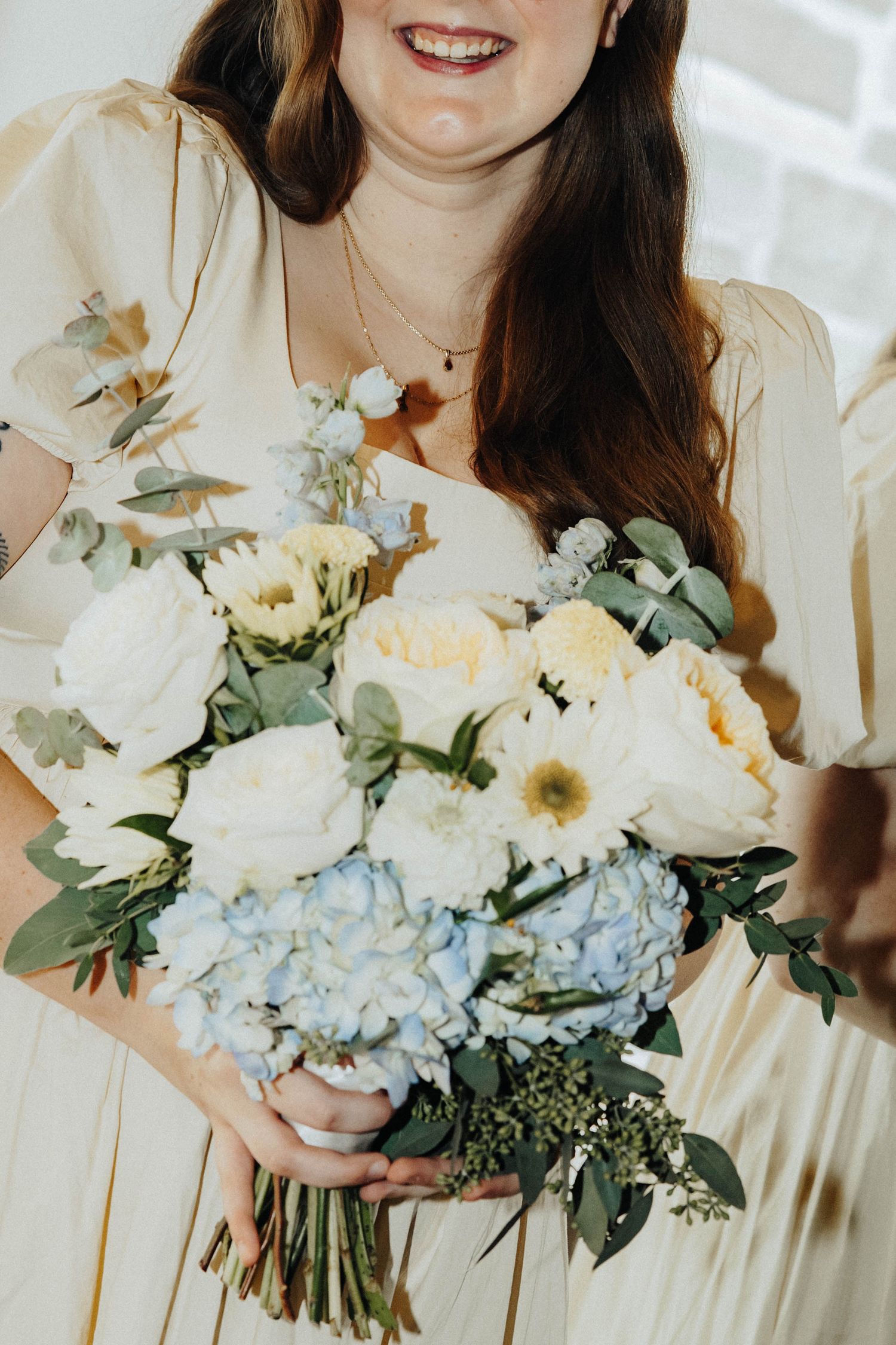 Elegant wedding bouquet featuring hydrangeas, roses, and eucalyptus in soft whites and pale blue tones.