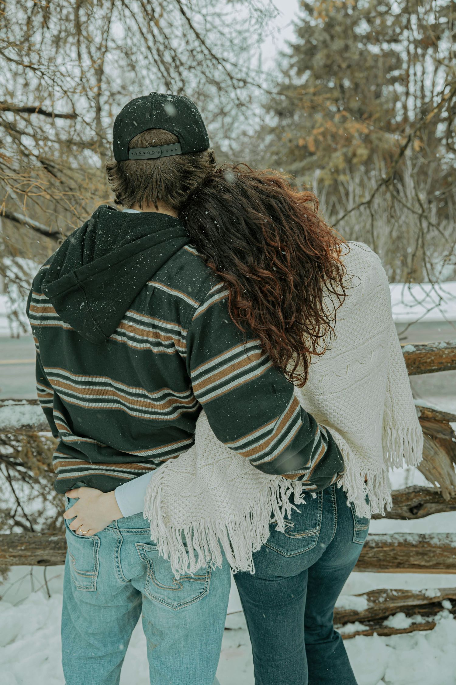 Two people in casual winter outfits walking together through snow-covered scenery.