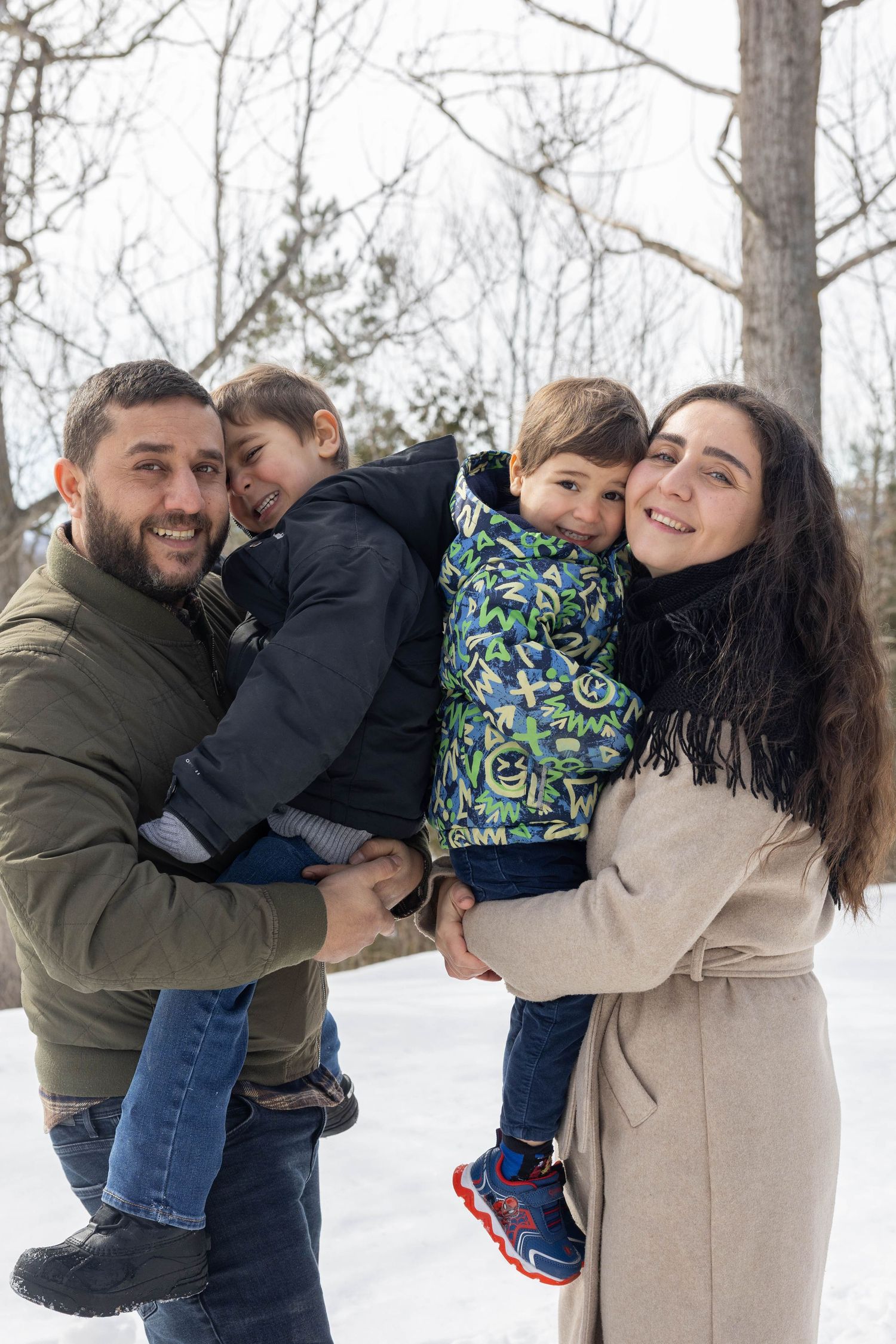 A family shares warm embraces and joyful moments together during a winter photoshoot in the snow.