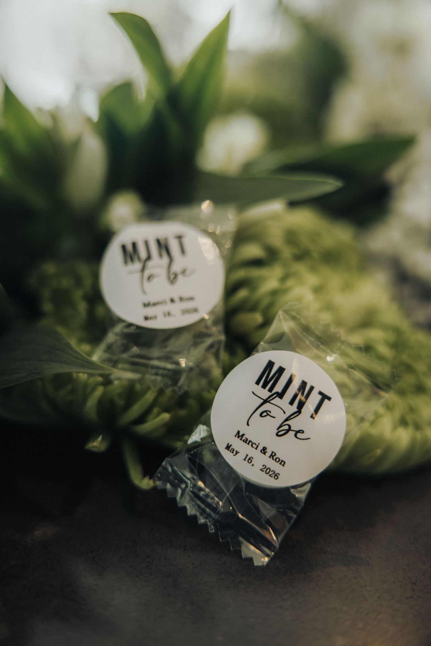 Wedding mint favors labeled Mint to Be for Marci and Ron, May 18, 2026, displayed with greenery.