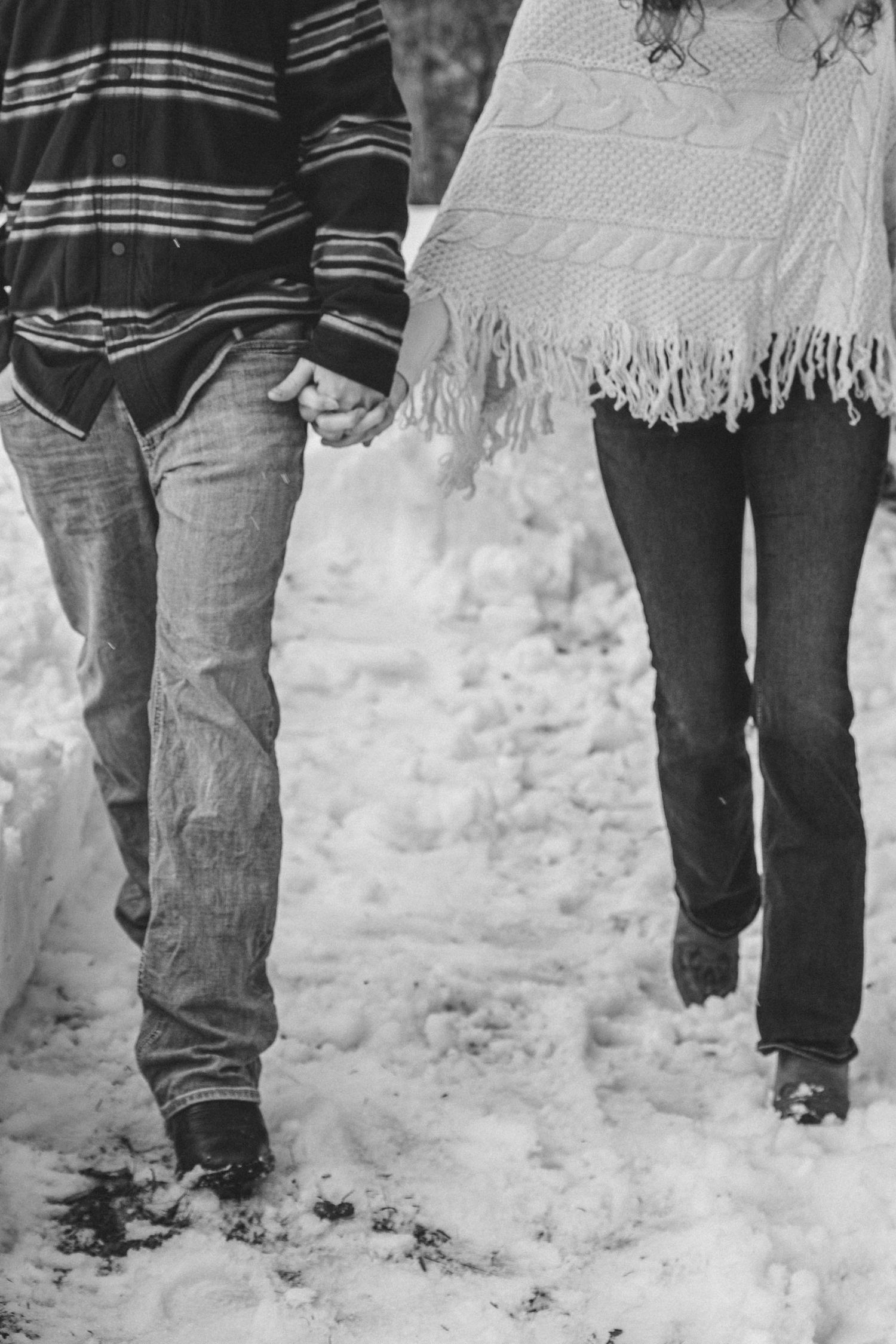A black and white photo showing multiple pairs of legs walking through fresh snow.
