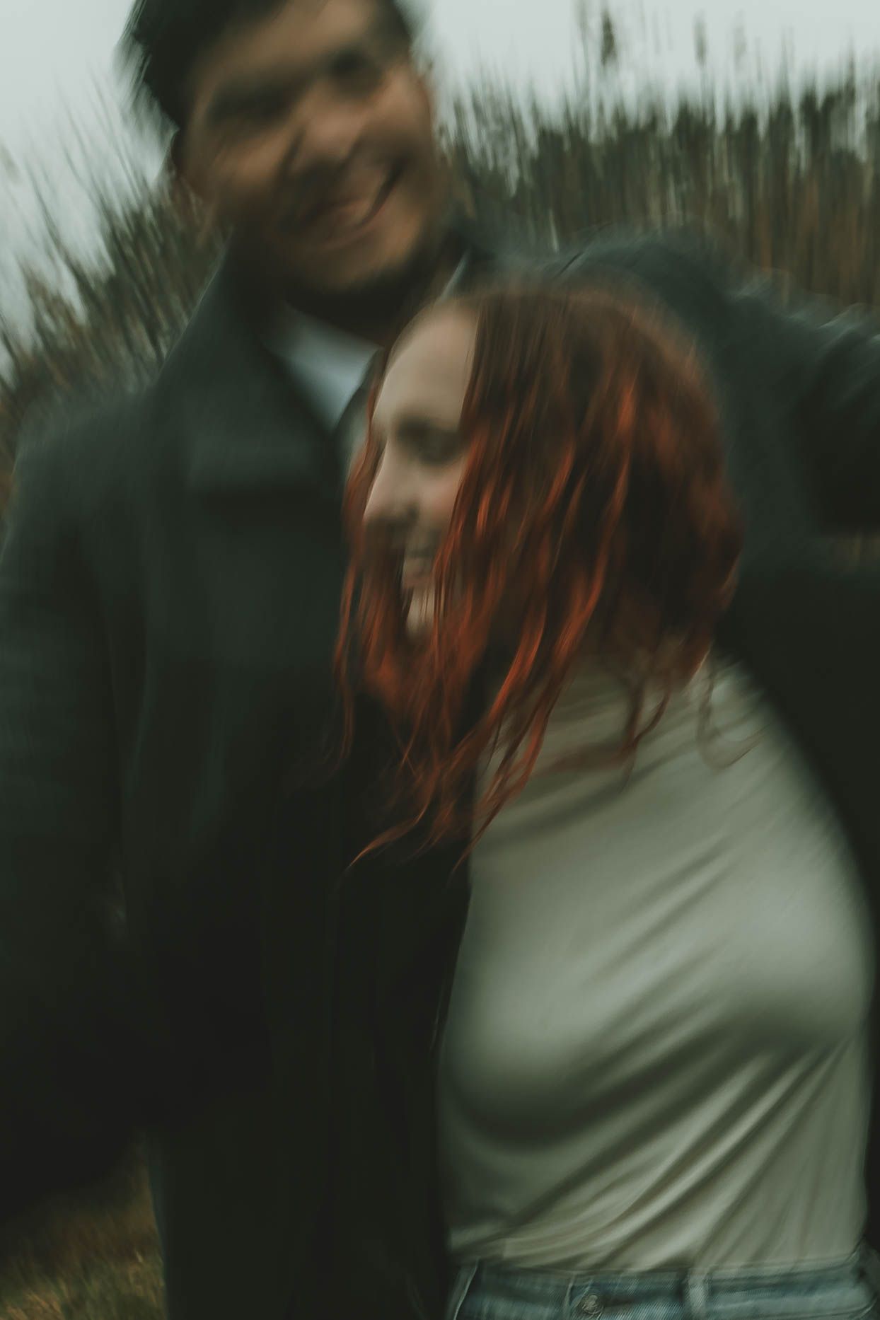 Artistic motion blur portrait in nature showing two people embracing with red hair flowing in the wind.