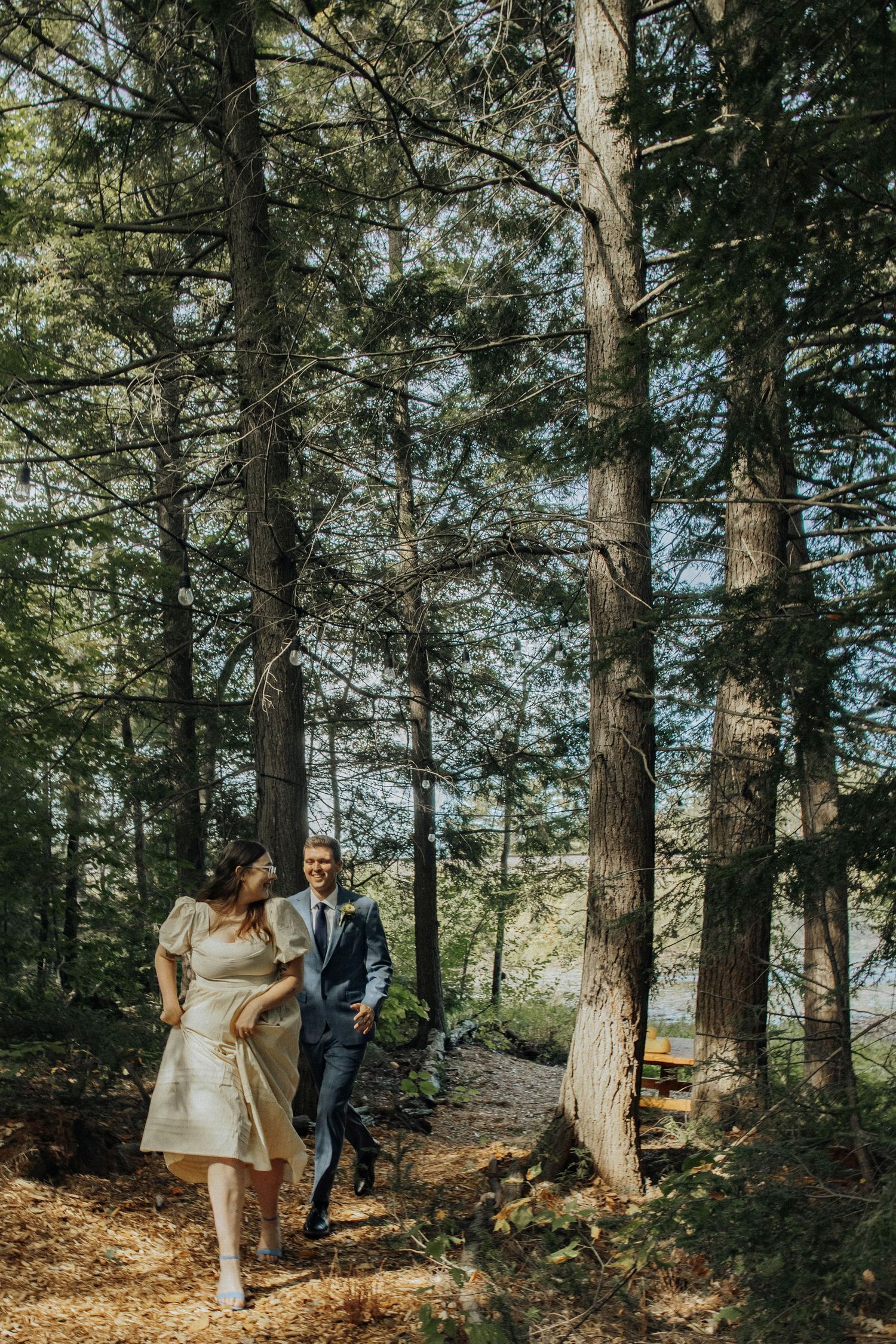 A romantic woodland setting with pine trees serves as backdrop for wedding photos.