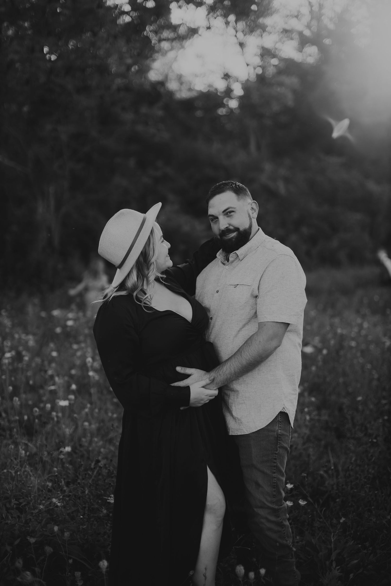 A romantic black and white photo sequence shows a couple embracing in a wildflower meadow at sunset.
