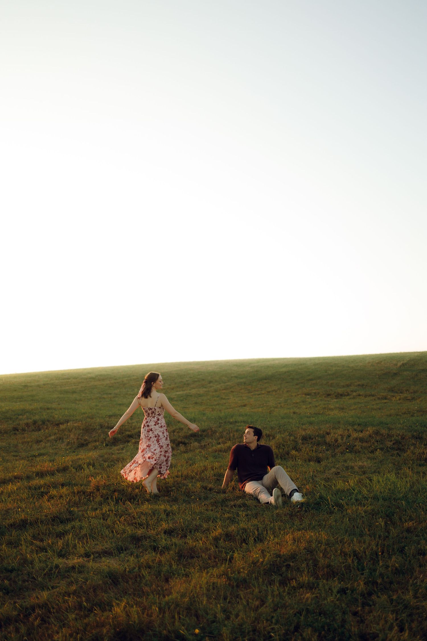 Two people enjoying a peaceful moment together on a grassy hillside at sunset.