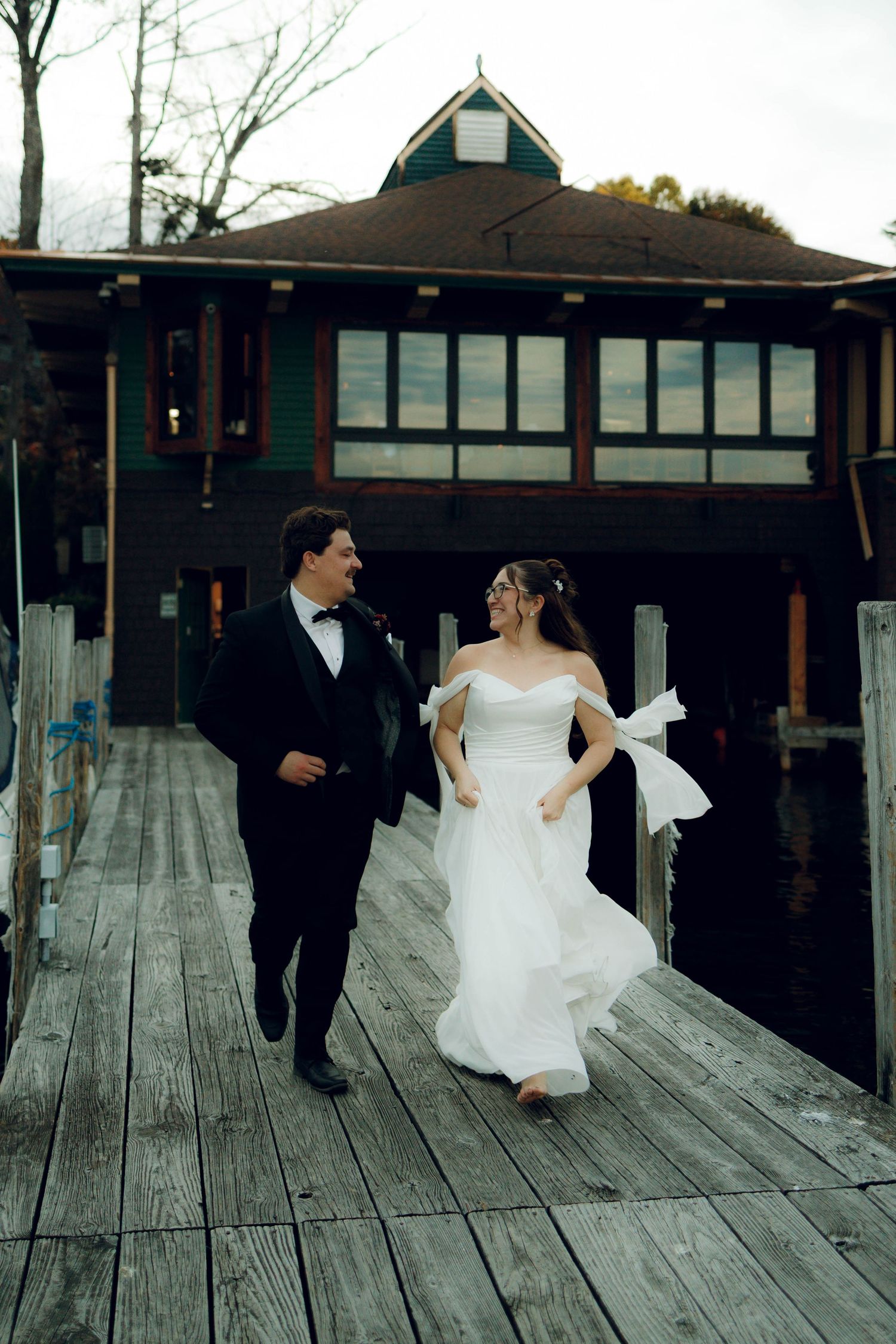 A couple in wedding attire dances playfully on a wooden deck in a sequence of candid black and white photos.
