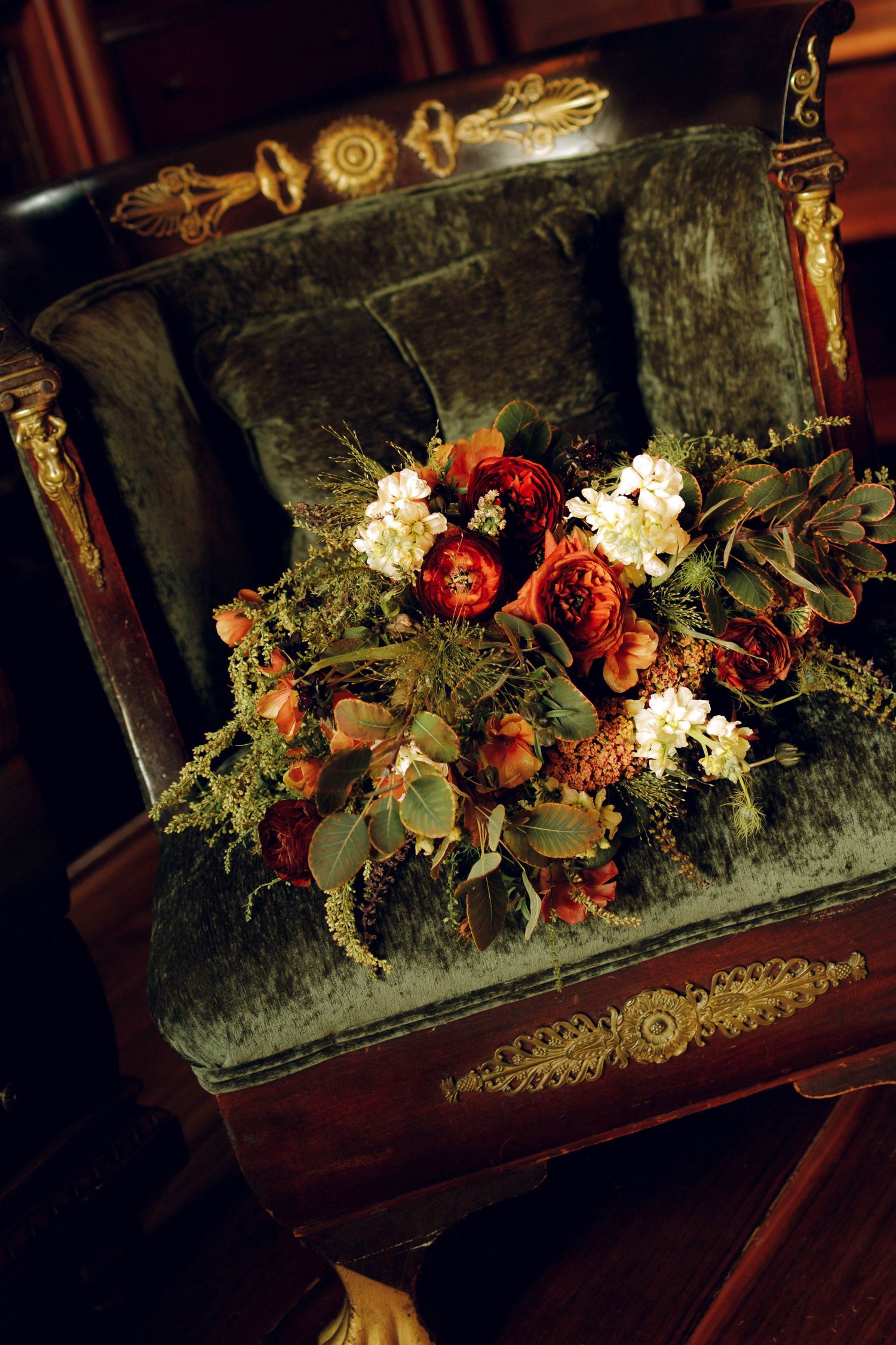 Dried red roses and greenery arranged in a vintage velvet-lined jewelry box create a romantic still life display.