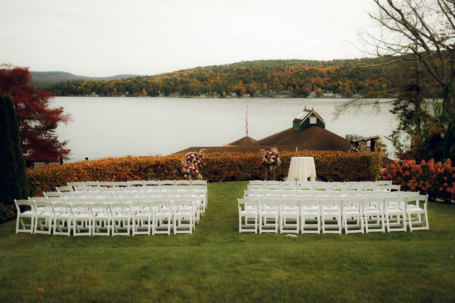 White chairs arranged in rows for an outdoor wedding ceremony with fall foliage and mountains in the background.