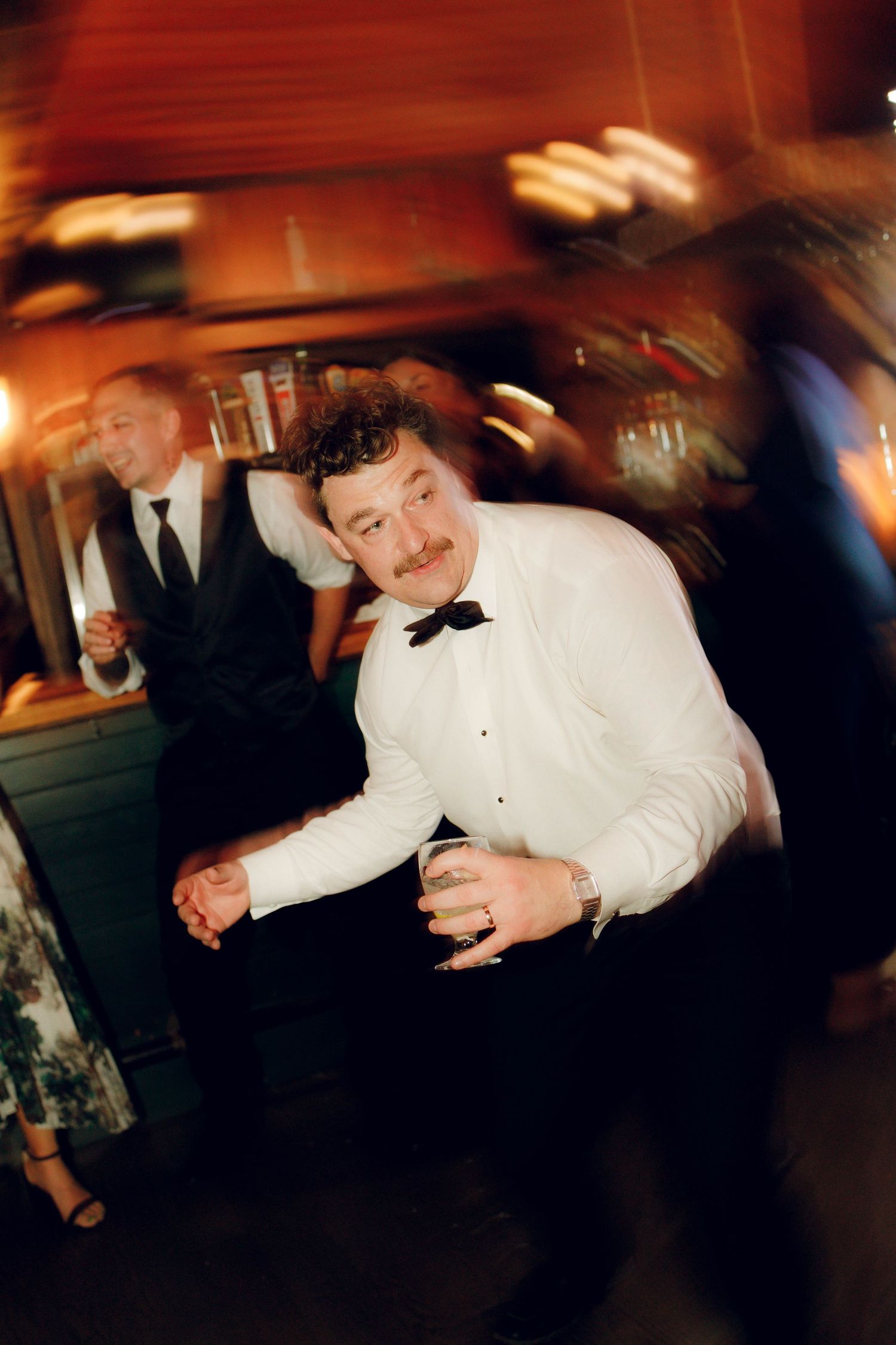A sequence of motion-blurred photos showing someone in a white shirt dancing energetically at a party or event.