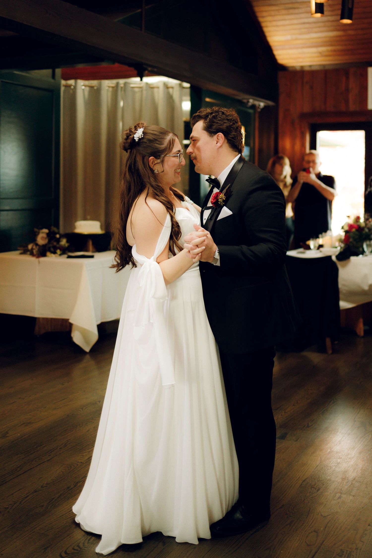 A bride and groom share their first dance together at their wedding reception on a wooden dance floor.