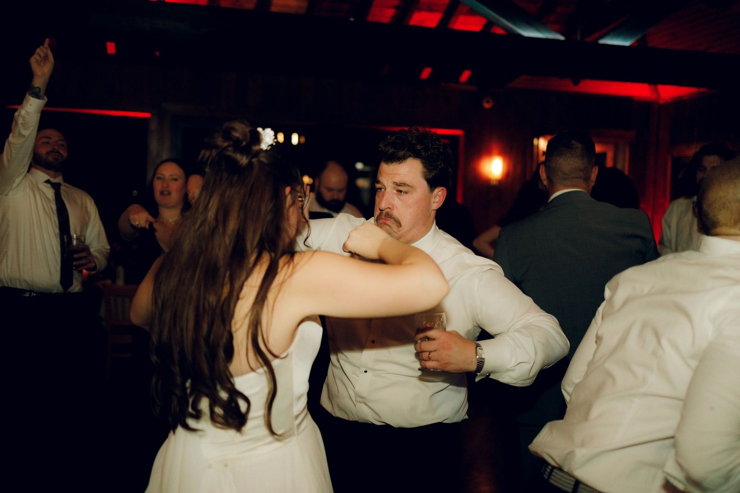 People dancing together in a dimly lit room with red lighting creating a romantic atmosphere.