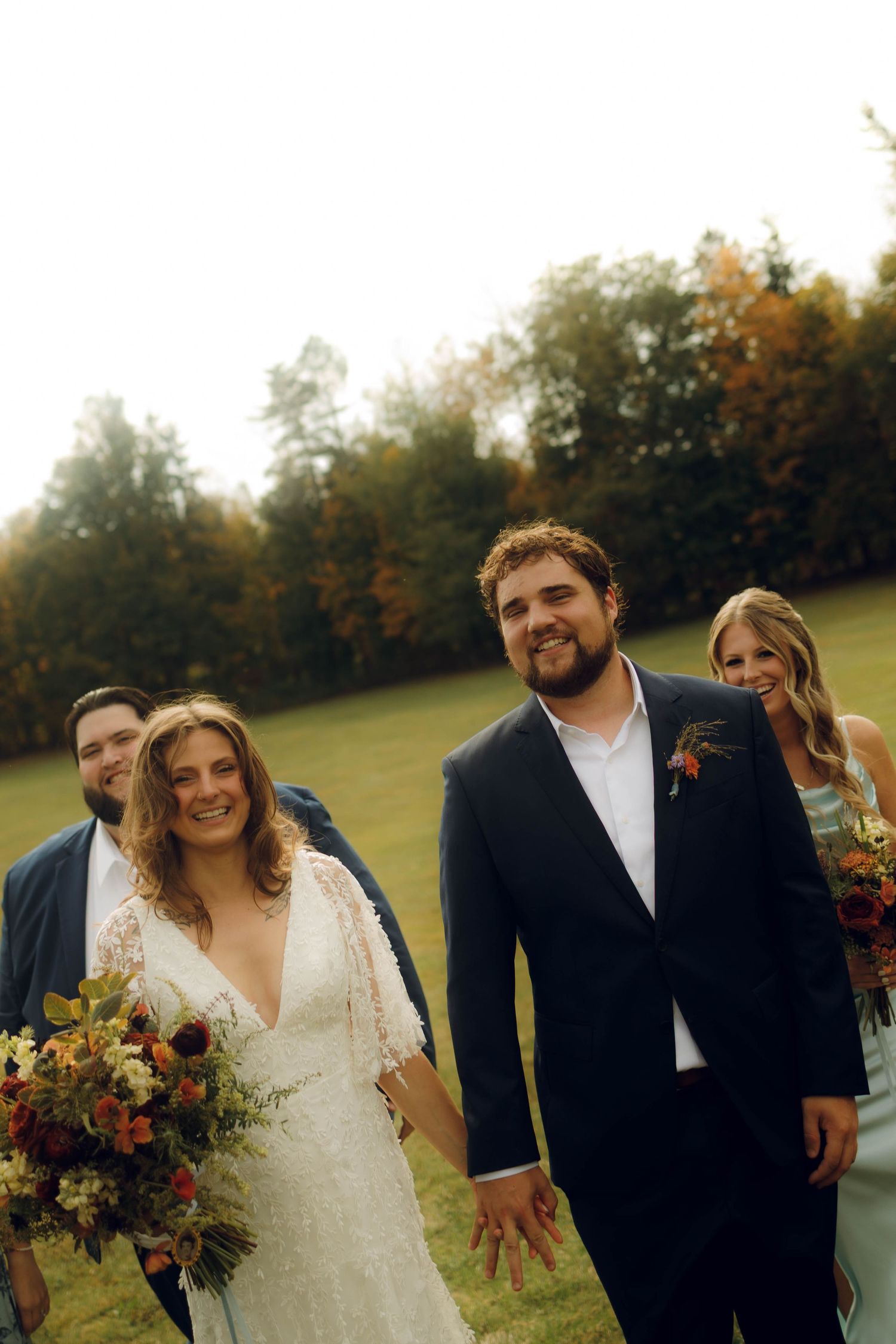 A couple shares a joyful moment in a field during their autumn wedding celebration with warm lighting.