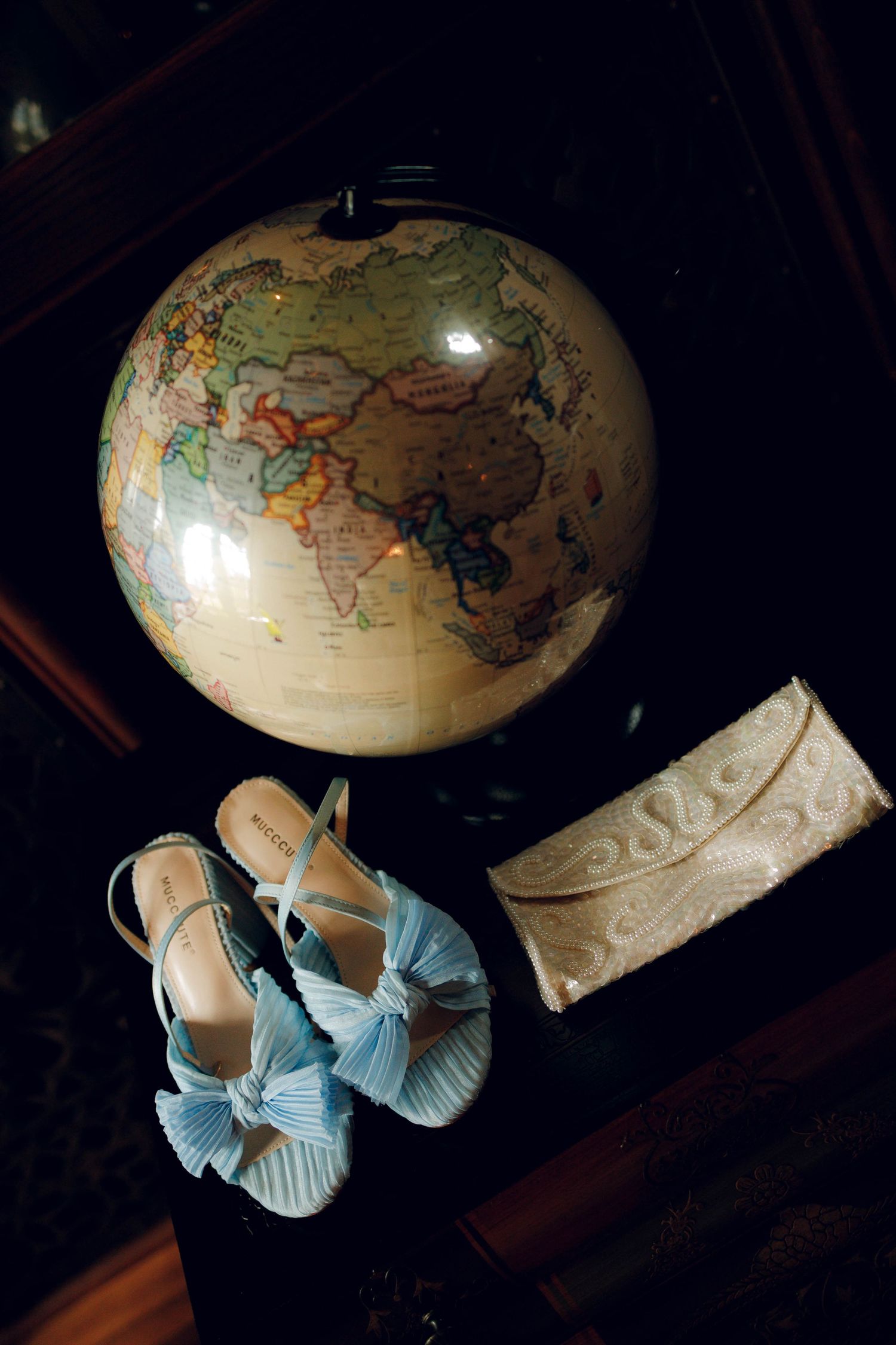 A vintage world globe lamp with blue ribbon decorations creates a warm atmospheric glow in a dark room.