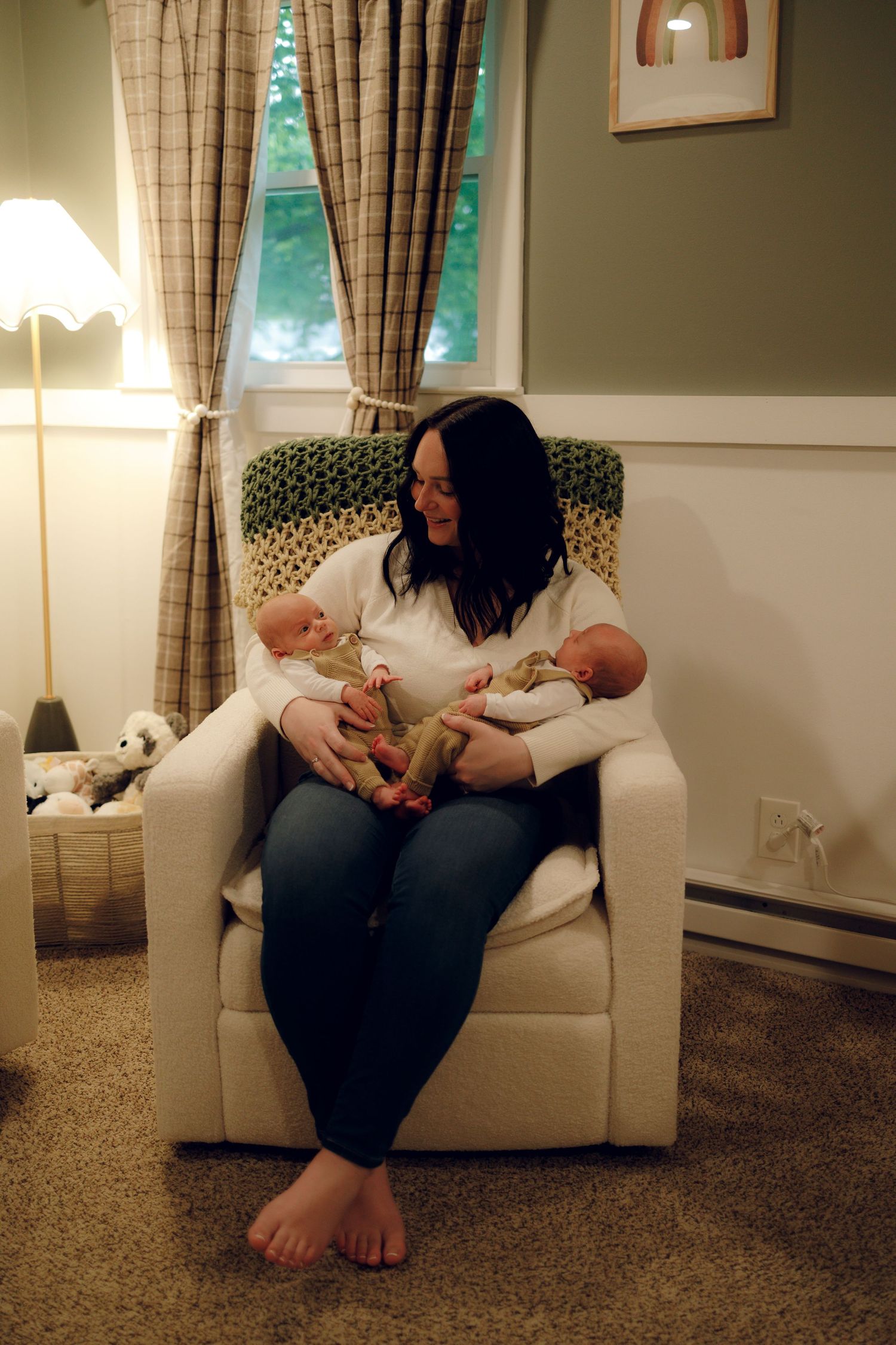 A peaceful moment in a cozy living room as twins are cradled together in a comfortable armchair.
